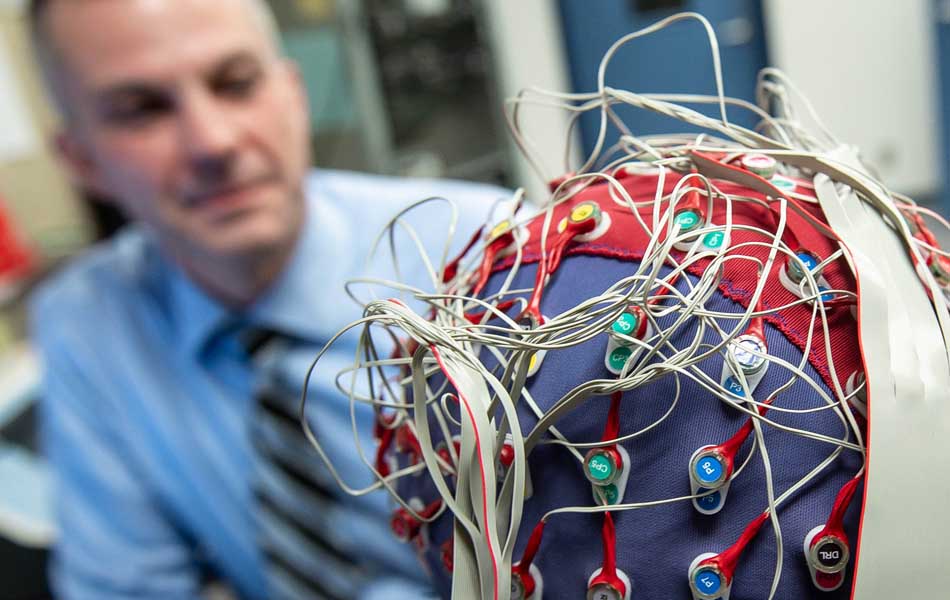 An image of Tony Herdman looking at a person wearing an EEG cap
