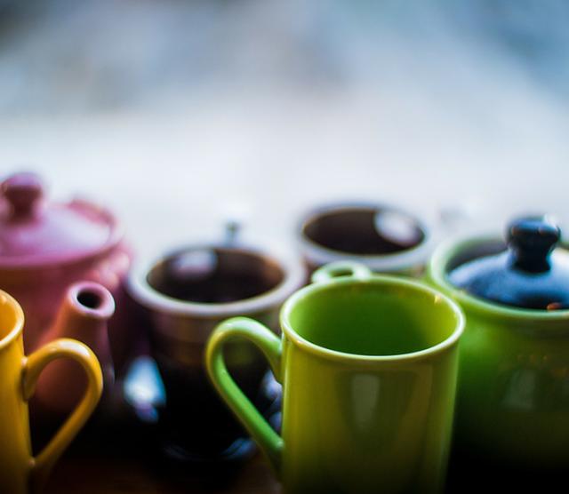 A close up of different coloured mugs and teapots