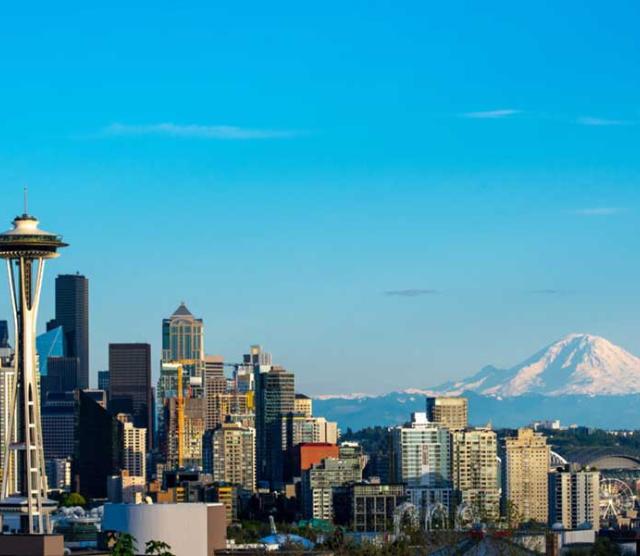 A photo of the Seattle skyline with blue sky and a mountain in the background