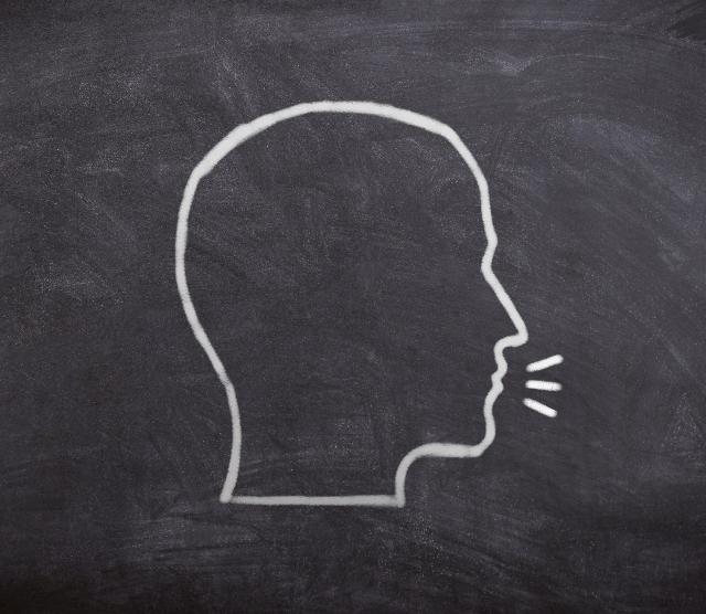 An image of a chalkboard with the outline of a human head, with speech marks, in white chalk