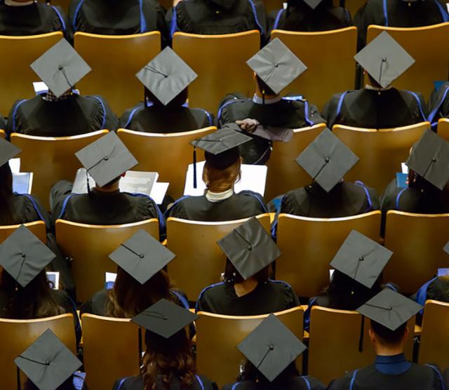 An eagle eye picture of UBC graduates sitting in rows facing forwards and wearing their graduation caps.