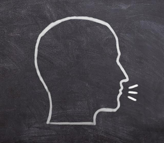 An image of a chalkboard with the outline of a human head, with speech marks, in white chalk