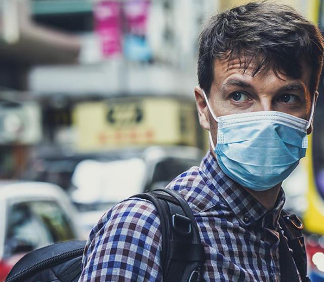 An image of a man wearing a surgical mask in a busy street