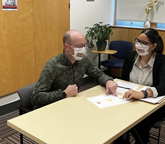 Speech Language Pathologist Student working with a client, both sitting at a table.