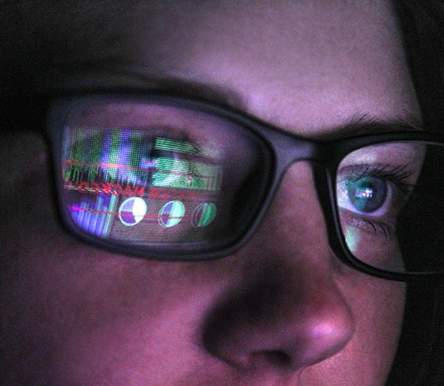 A close up of a woman wearing glasses with a screen reflected on the glasses