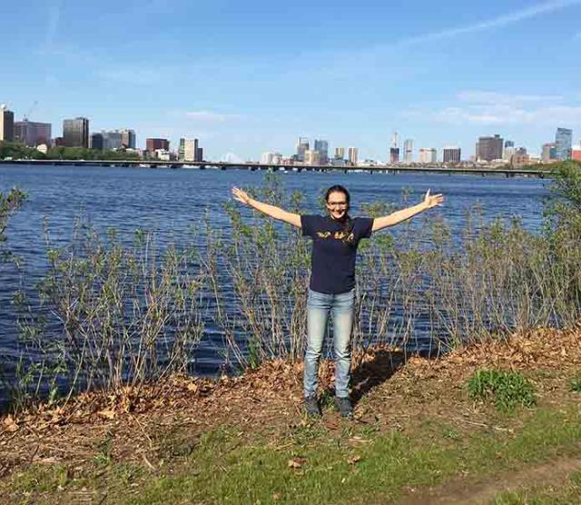 A photo of Paris standing in front of Boston harbour with her arms spread