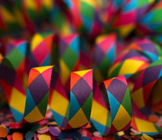 A close up of rainbow coloured confetti tape, sitting in loops on a flat surface