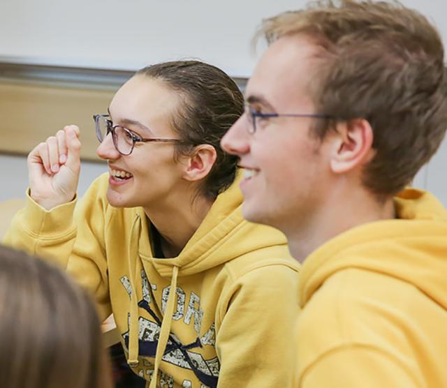 A close up of Paris laughing, and Kelton smiling, both dressed in yellow