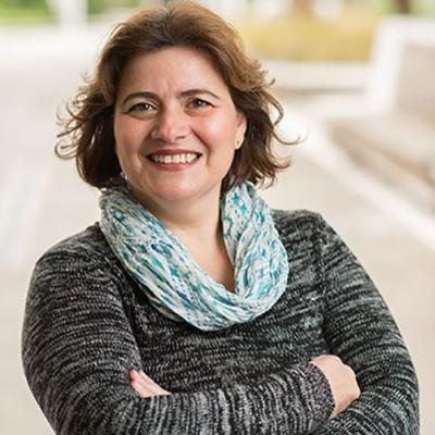 A headshot of Roberta Ballarin standing outside with her arms crossed, smiling