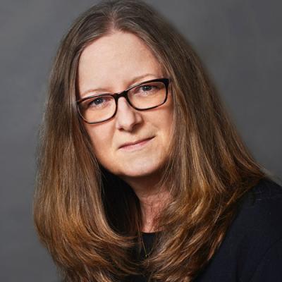 A headshot of Sherri K Zelazny against a grey background