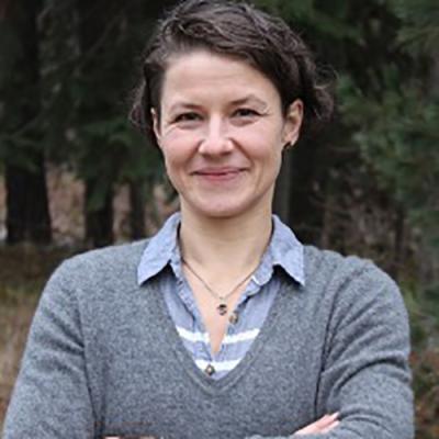A headshot of Sonja Thoma standing outside with arms crossed, smiling